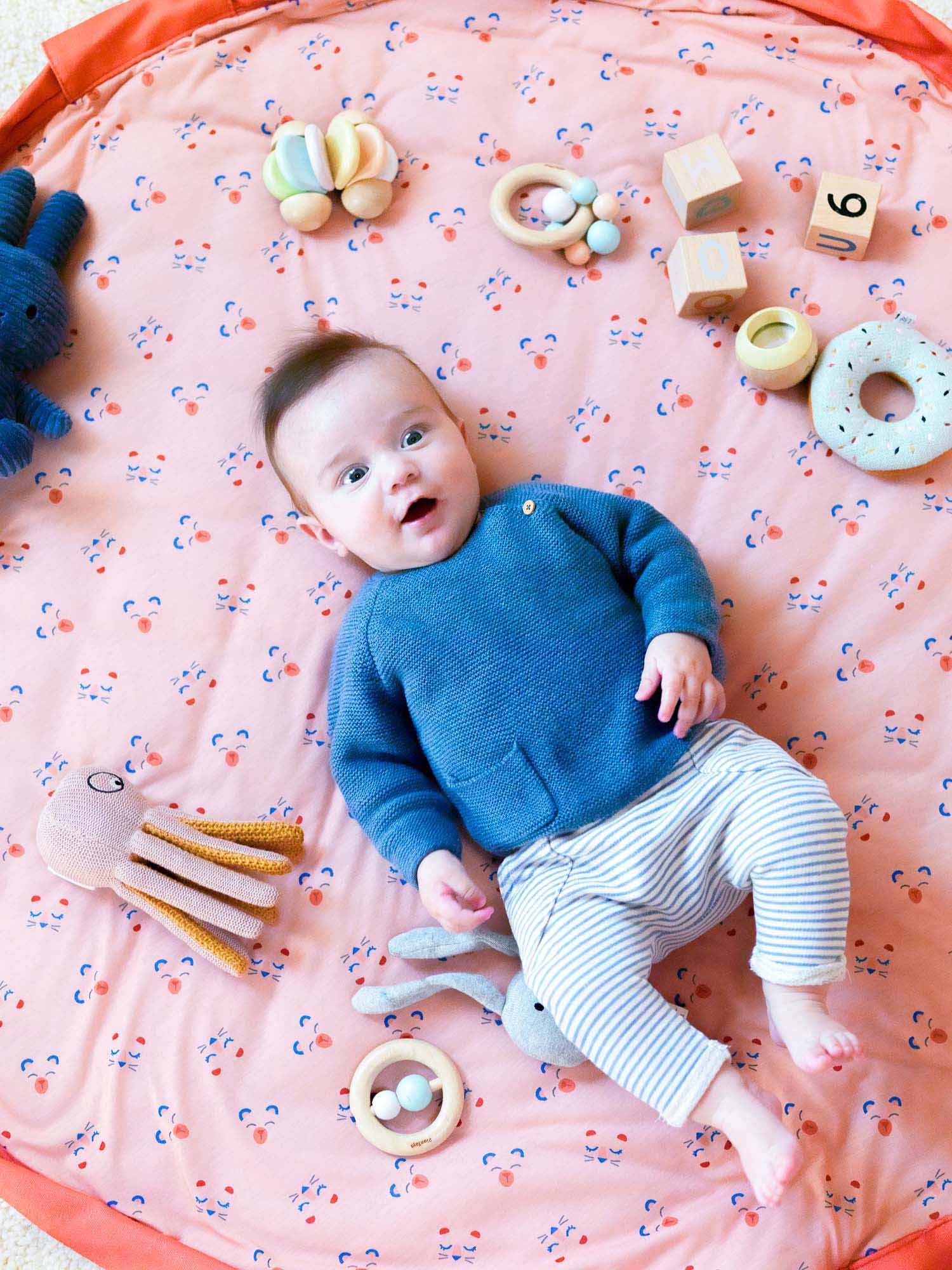 Play&Go Soft print animal faces, coral, padded playmat, storage bag, diaper bag. baby lying between blocks