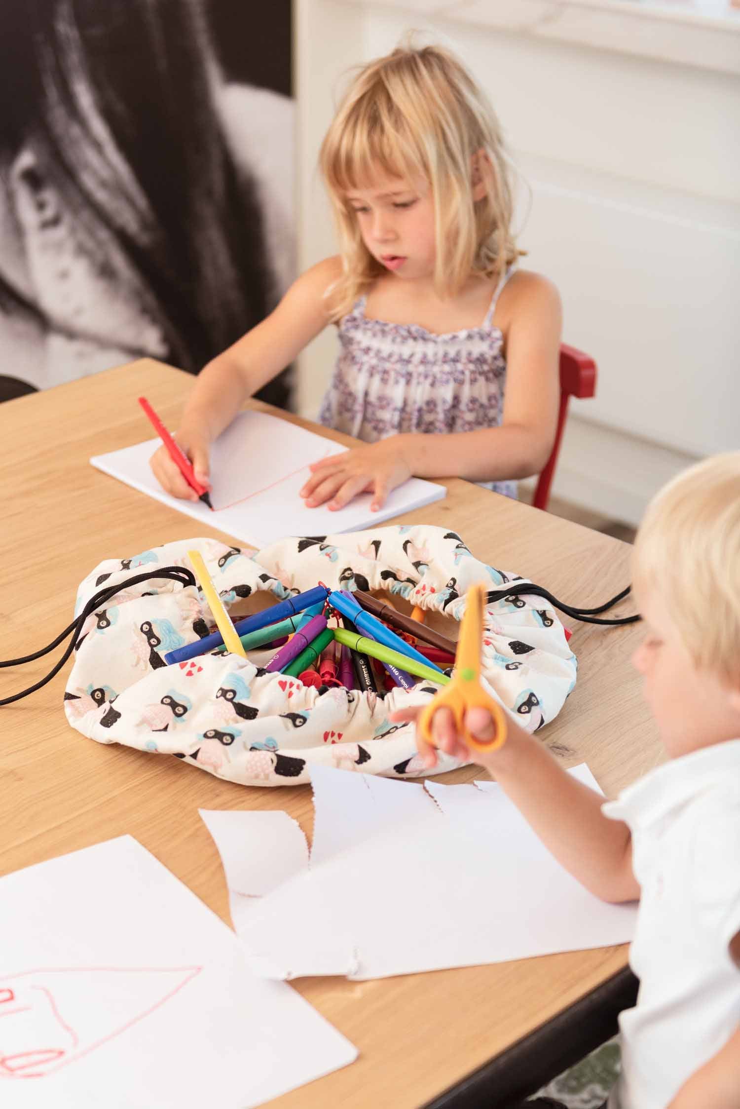 supergirl mini toy storage bag, filled with pencils, 2 kids drawing