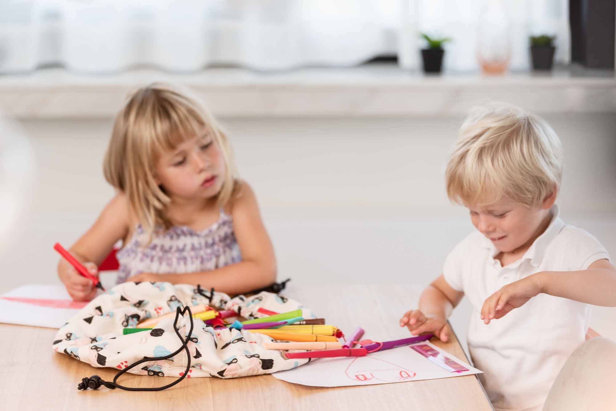 supergirl mini toy storage bag, filled with pencils, 2 kids drawing