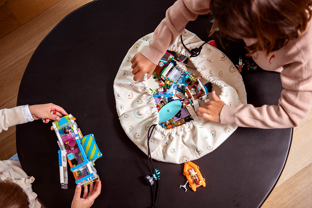 Play&Go mini storage bag, print rainbow, filled with lego, 2 girls playing at table