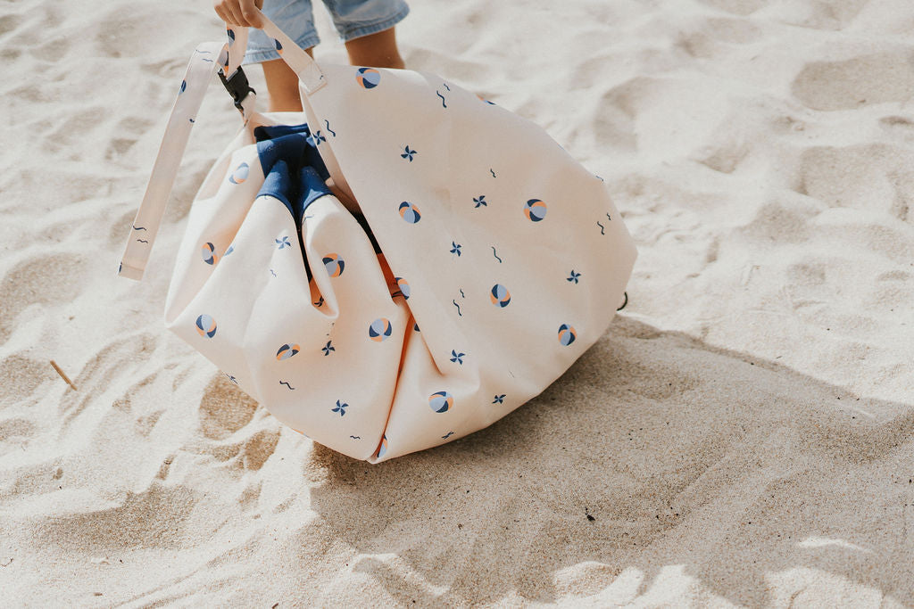 Play&Go outdoor storage bag and play mat, print balloon, kid on the beach carrying the bag