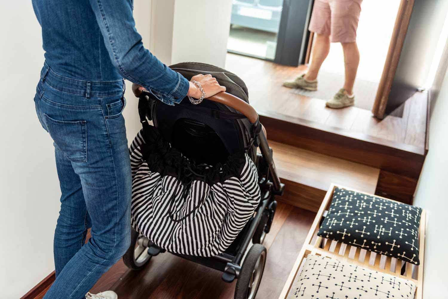 Play&Go storage bag and soft padded baby mat, woman walking with pram, black and white striped bag hanging on pram