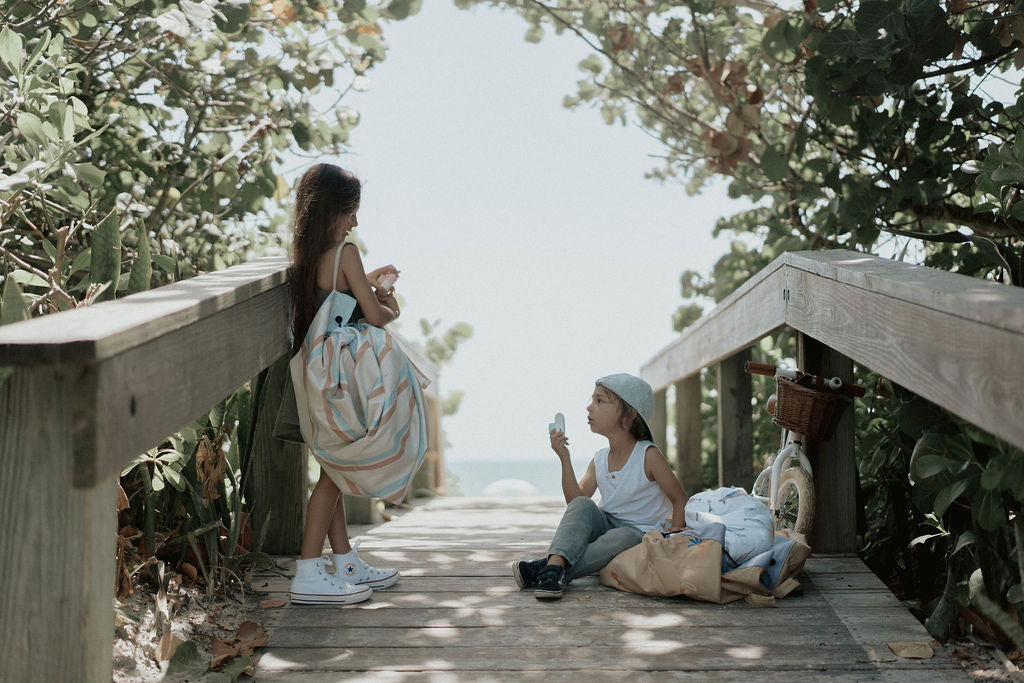 Play&Go outdoor storage bag and play mat, stripes, girl carrying bag, bicycle, little boy with cap sitting on bridge