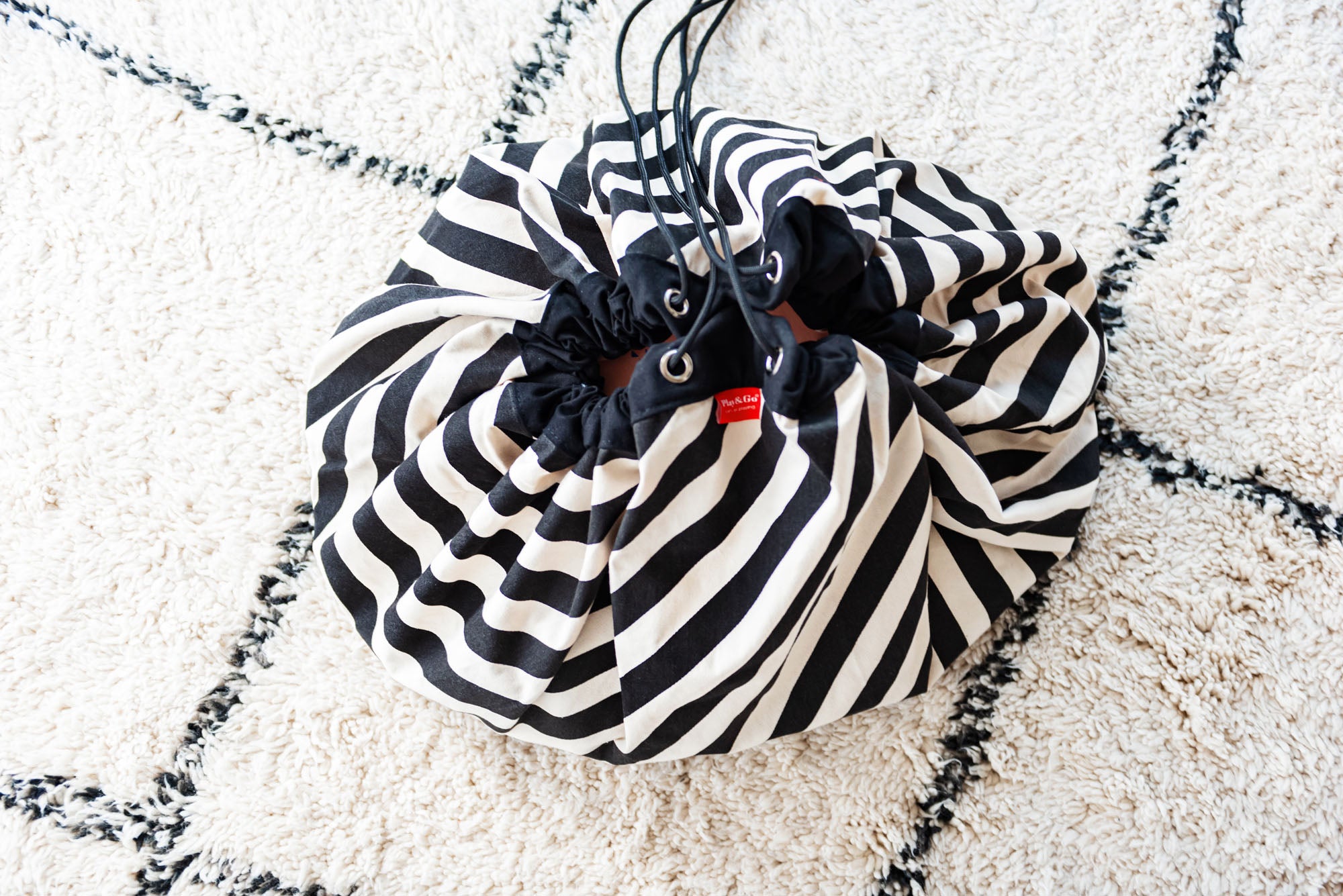 product picture toy storage bag and play mat, black and white stripes, bag on carpet