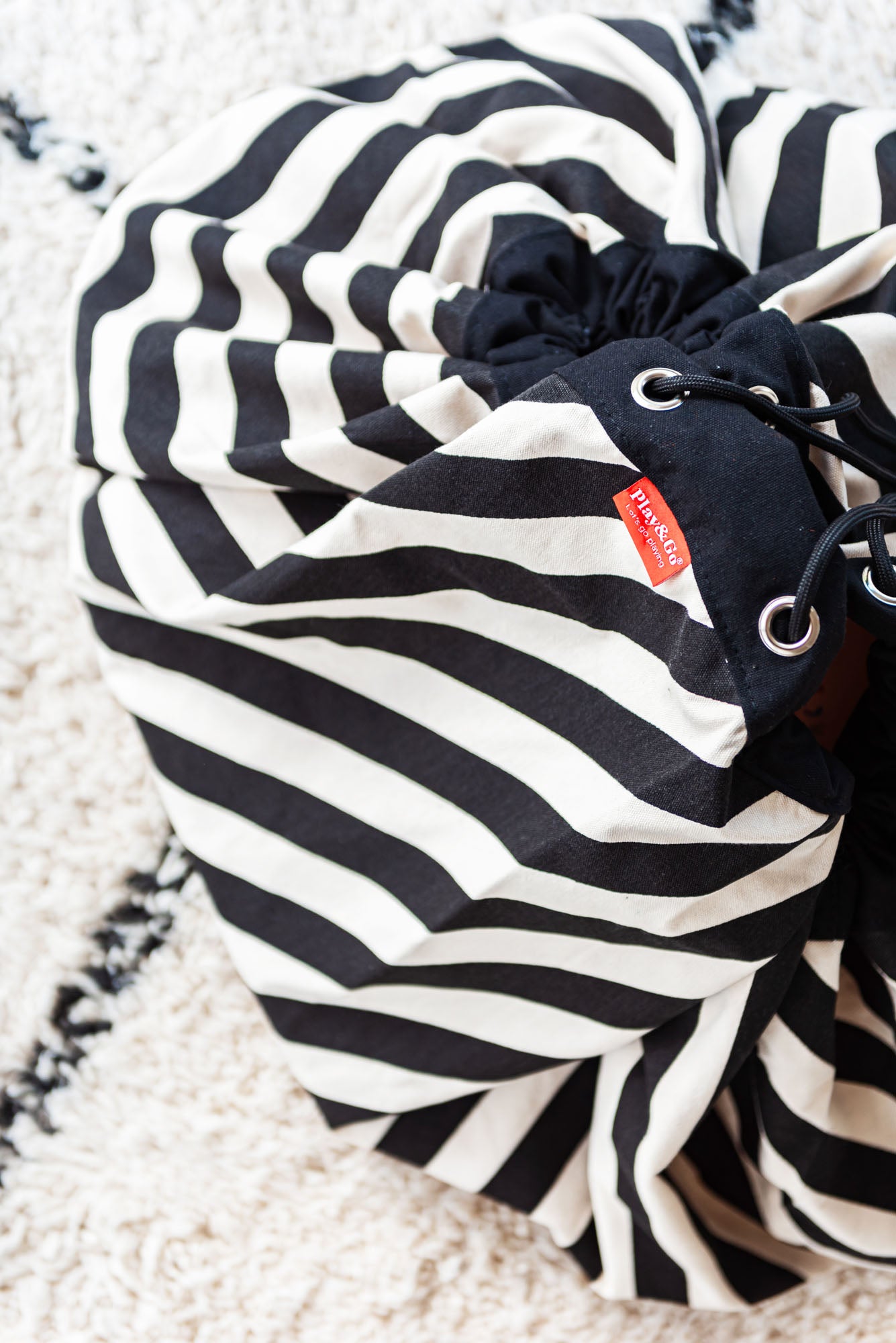 product picture toy storage bag and play mat, black and white stripes, bag on carpet