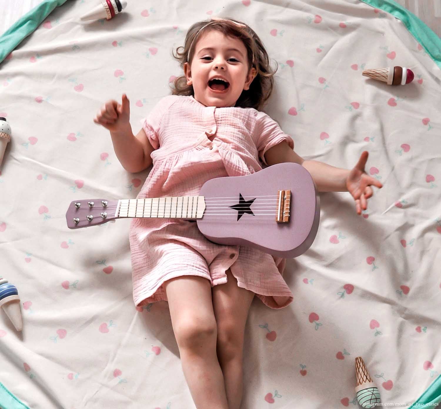 Play&Go storage bag and play mat, print cherry love, open, girl lying on mat with purple guitar and ice cream toys